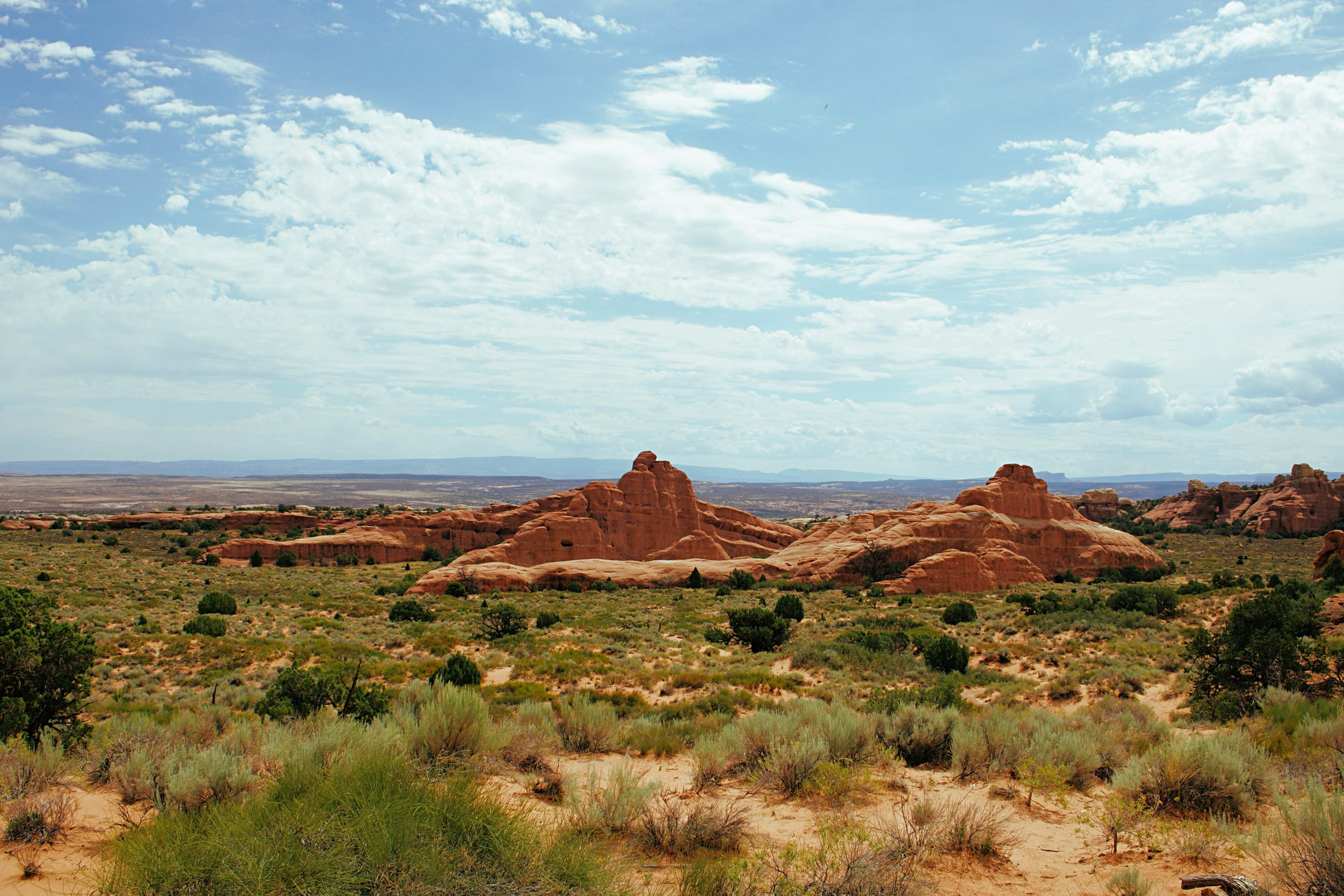 An RV parked in a scenic Southern Utah campground with red rock formations and wildflowers in bloom.